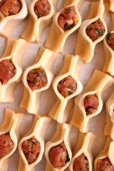 many small appetizers are lined up on a sheet of parchment paper, ready to be eaten