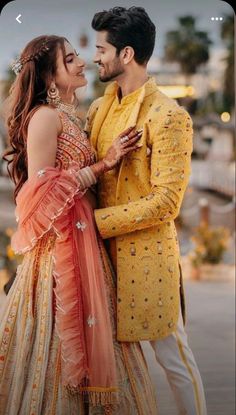 a man in a yellow suit and woman in a pink dress standing next to each other