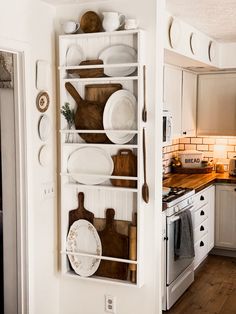 a kitchen with white cupboards and wooden utensils on the shelves above the stove