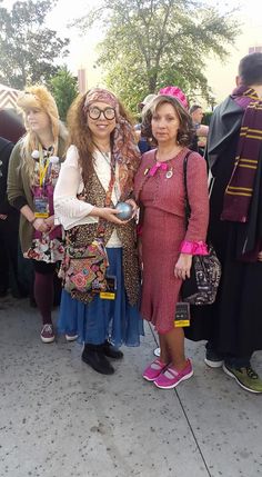 two women standing next to each other in front of a group of people wearing costumes