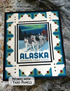 the alaska poster is hanging on the wall next to a stone wall with an image of three husky dogs