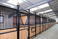 the inside of a stable with wooden stalls and black iron railings on each side