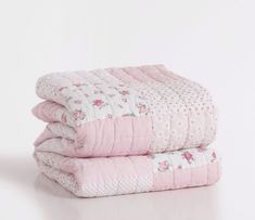 two pink and white quilts stacked on top of each other in front of a white wall