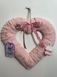 a pink heart shaped wreath with a cupcake hanging from it's side on a hook