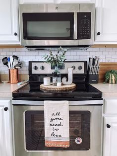 a kitchen with white cabinets and stainless steel appliances, including a black stove top oven