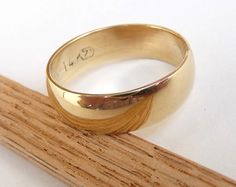 a yellow gold ring sitting on top of a wooden stick with the word i love you written on it