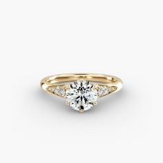 a yellow gold engagement ring with three stones on the side and a diamond in the center