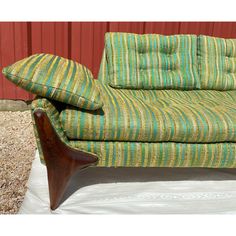 a green striped couch sitting on top of a white sheet next to a red wall