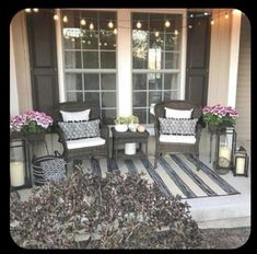 two wicker chairs sitting on top of a striped rug next to a window filled with flowers