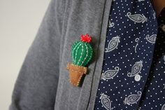 a cactus brooch is attached to a man's gray shirt and blue polka dot tie