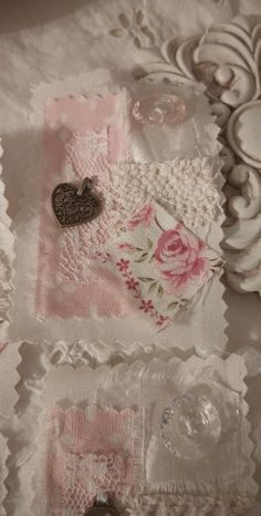 some lace and buttons are laying on a tablecloth with flowers, hearts, and other things