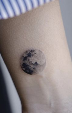 a person's arm with a small tattoo of the moon and stars on it