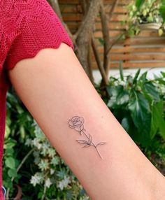 a woman's arm with a single rose tattoo on the left side of her arm