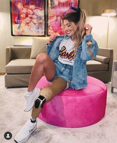 a woman sitting on top of a pink ottoman