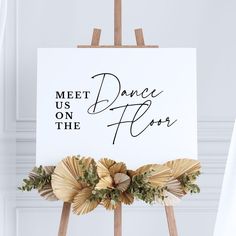 a sign that says meet us on the dance floor with flowers in front of it