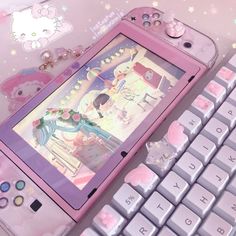 a pink hello kitty phone sitting next to a keyboard