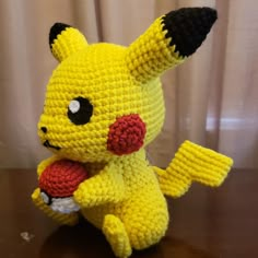 a crocheted pokemon stuffed animal sitting on top of a wooden table next to a curtain