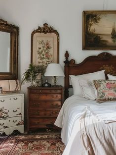 a bed sitting in a bedroom next to two dressers and a painting on the wall