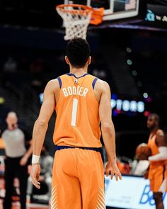 a basketball player in an orange uniform standing on the court