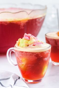 two glasses filled with drinks sitting on top of a white table next to each other