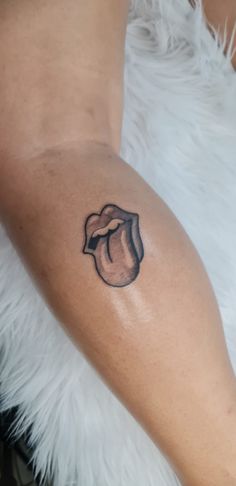 a woman's arm with a small black and grey lip tattoo on her left side