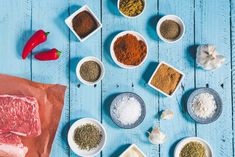 various spices and seasonings in bowls on a blue wooden table