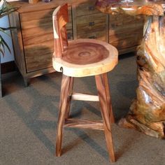 a wooden stool sitting next to a tree stump in front of a dresser and mirror