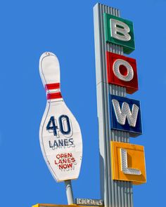 a large bowling ball sitting on top of a tall pole next to a sign that says bowling lanes