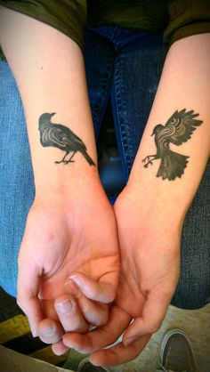 two people holding hands with tattoos on their arms and one has a bird on it