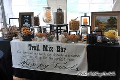 a table topped with lots of candy and candies next to a sign that says trail mix bar