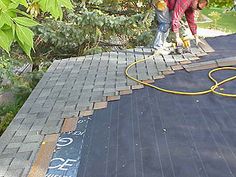 two men are working on the roof of a house