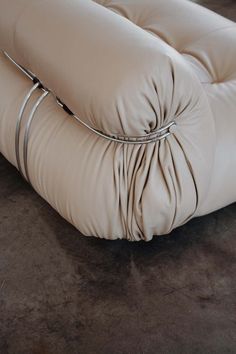 the back end of a beige leather couch with metal straps on it's sides