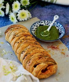 a croissant with pesto on it next to a bowl of dip