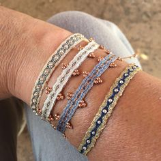 a woman's arm with four different bracelets on top of each other,