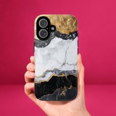 a hand holding an iphone case with gold and black marble design on it, against a pink background