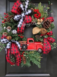 a red truck is sitting in front of a wreath with pine cones and evergreens