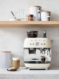 an espresso machine sitting on top of a counter next to cups and mugs