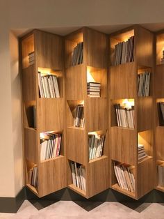 a wooden book shelf with many books on it's sides and lights in between them