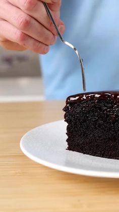 a person cutting into a piece of chocolate cake