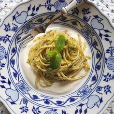 a white plate topped with pasta covered in pesto