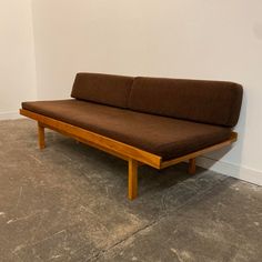 a brown couch sitting on top of a cement floor next to a white walled wall