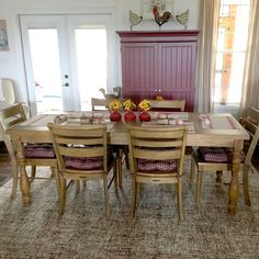 a dining room table and chairs with flowers on the placemats in front of them