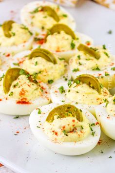 deviled eggs with jalapeno peppers and cheese on a white platter