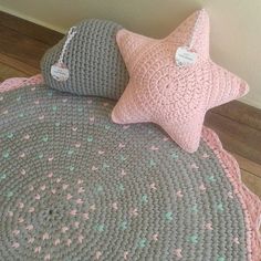 two crocheted pillows on top of a bed with a pink and gray blanket