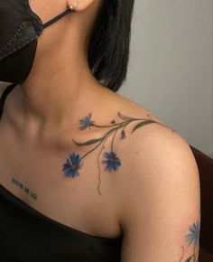 a woman with blue flowers on her chest wearing a face mask and covering up her mouth