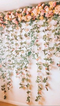 the wall is covered with pink flowers and greenery hanging from it's sides