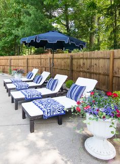 lounge chairs with blue and white cushions are lined up in front of a fenced area