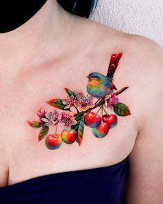 a woman's chest with an apple tree and bird tattoo on her left shoulder