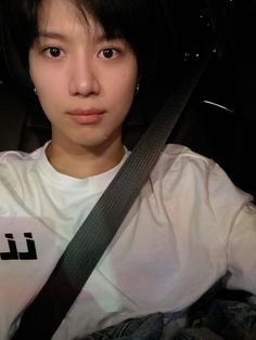 a woman sitting in the back seat of a car wearing a white shirt and black belt