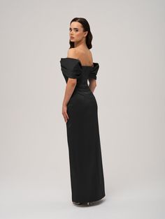 a woman in a long black dress is looking back at the camera and she has her hands on her hips